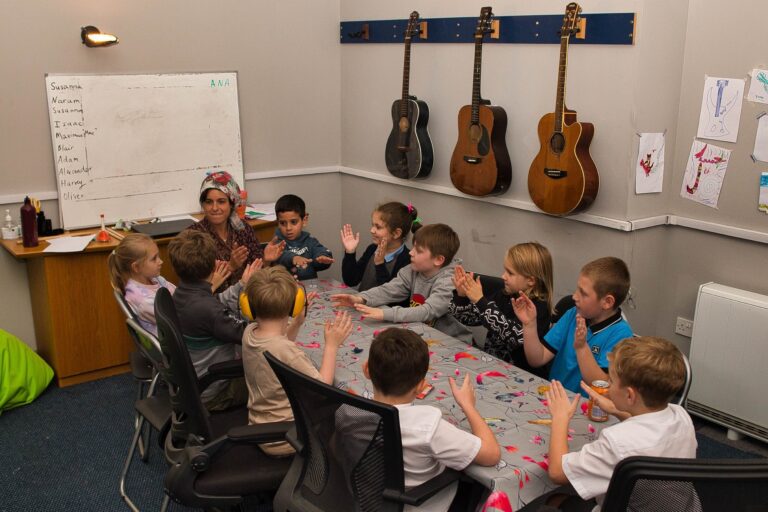 children in glagsgow in a small group learning music together